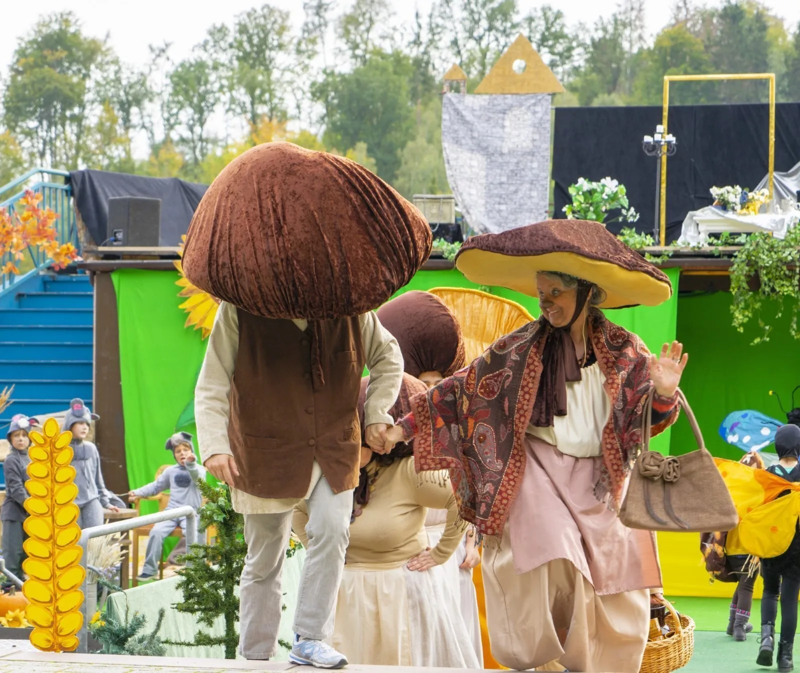 Pilze im Wald: Steinpilz und Nachbarin auf der Bühne – Zwei Pilzfiguren mit großen braunen Hüten betreten die Stufen, im Hintergrund huschen Mäuse