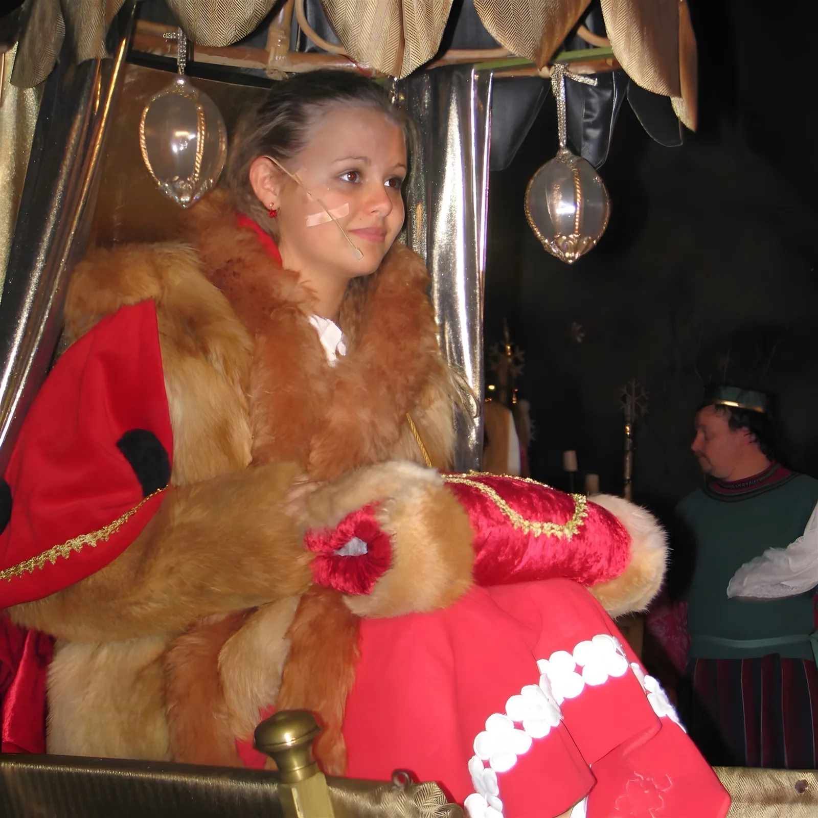 Gerda auf dem goldenen Schlitten ? Gerda in rotem Umhang und Fell sitzt nachdenklich in einem geschmückten Schlitten, glitzernde Laternen hängen über ihr – Aufbruch in die wintrige Suche.