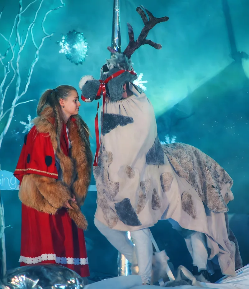 Gerda trifft das Rentier im Eispalast ? Gerda im roten Mantel begegnet einem kostümierten Rentier mit Geweih vor eisblauer Kulisse, Schneeflocken glitzern – Bündnis für die Rettung.