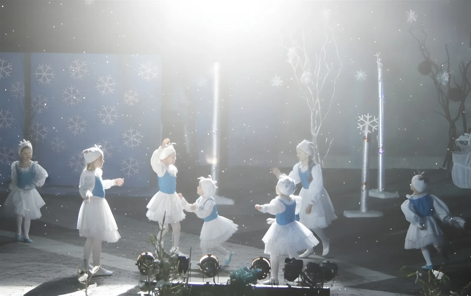 Tanz der Schneeflockenkinder ? Mehrere Kinder in weißen Tutus und blauen Westen tanzen im leichten Schneefall – heiterer Reigen des Winters.