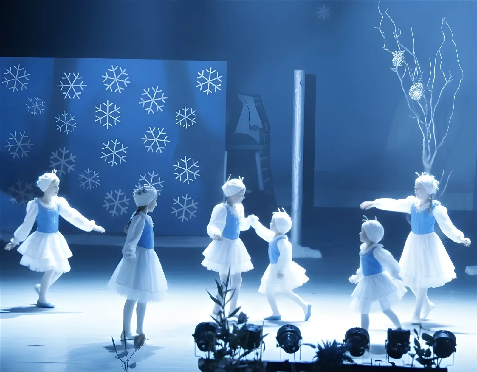 Schneeflockenreigen im blauen Licht ? Kinder in weißen Röcken und blauen Westen fassen sich an den Händen, Schneeflocken schmücken den Hintergrund – poetische Winterchoreografie.