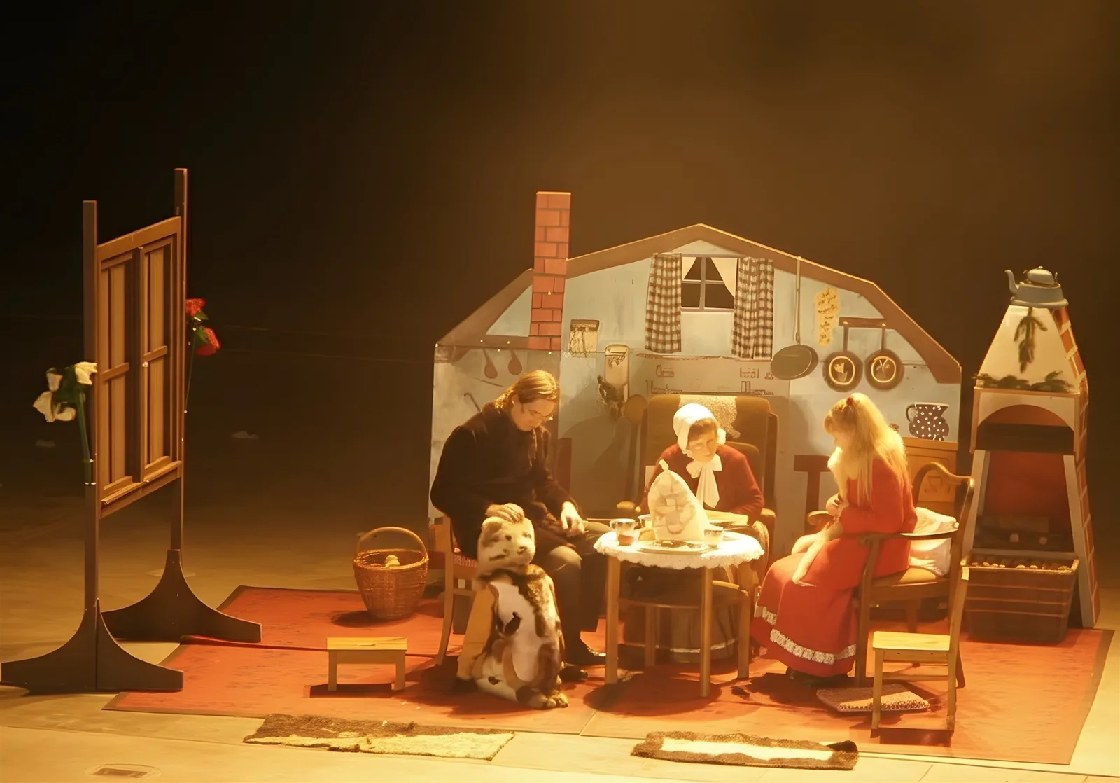 Kay, Gerda und Großmutter mit Kätzchen ? Kay und Gerda sitzen bei der Großmutter am Tisch, das Kätzchen liegt vor ihnen, die Stube ist liebevoll bemalt – Zuhause vor dem Abenteuer.