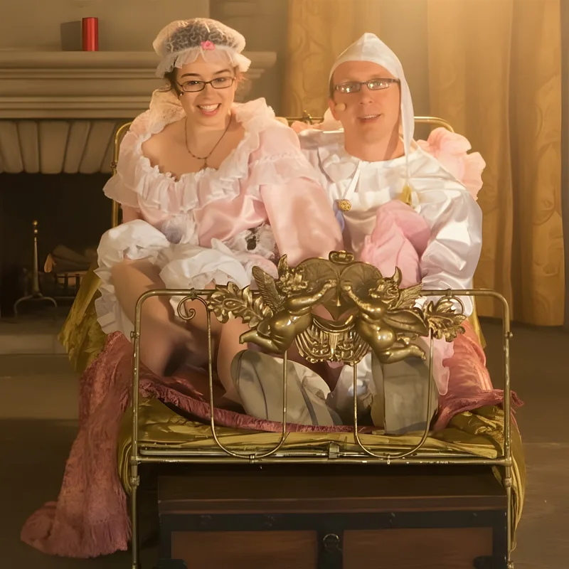 Prinz und Prinzessin im Himmelbett ? Der Prinz und die Prinzessin im rosa und weißen Schlafgewand sitzen lachend im goldenen Bett – komische Hofszene auf der Reise.