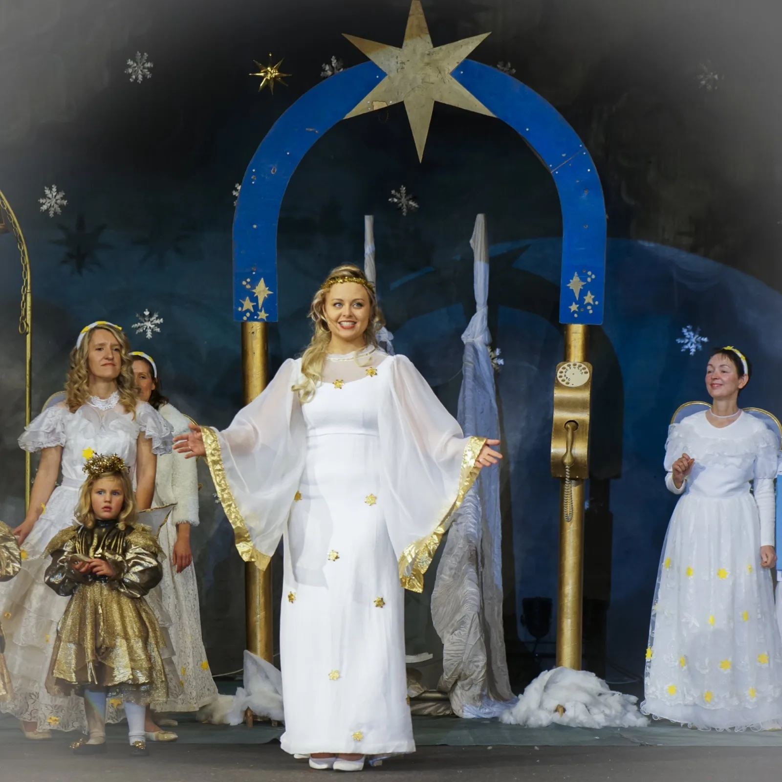 Christkind und Engel am Sternentor – Das Christkind in weiß-goldener Robe begrüßt unter einem blauen Sternentor mehrere Engel in weißen Kleidern vor winterlicher Kulisse – himmlische Szenerie des Himmelszelts.