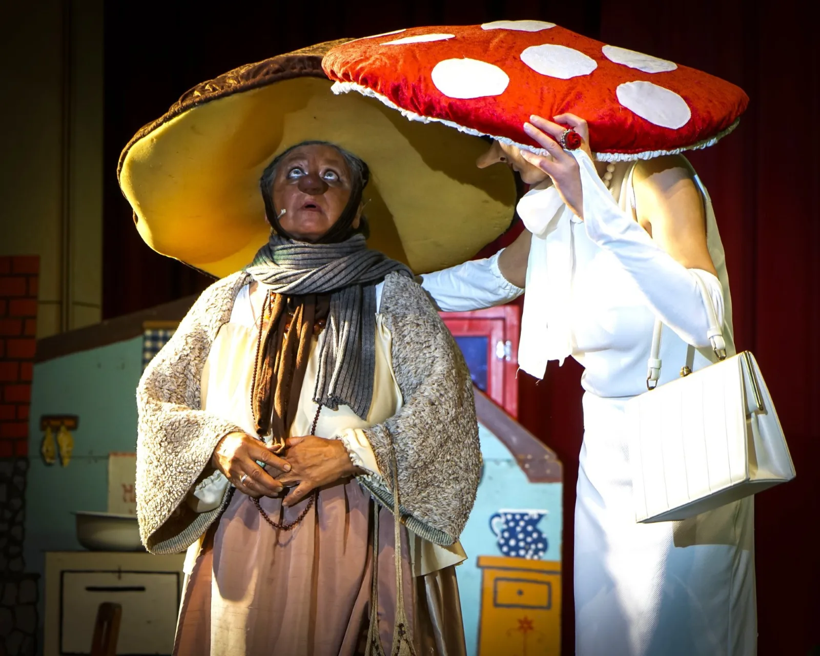 Frau Steinpilz und Frau Fliegenpilz treffen den Hexenmeister – Zwei Pilzfiguren mit übergroßen Hüten, Steinpilz und Fliegenpilz, stehen nebeneinander und tauschen sich aus – humorvolle Waldszene.