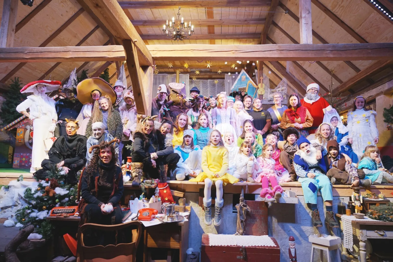 Großes Ensemblefoto mit Weihnachtsmann – Darstellerinnen und Darsteller aller Figuren versammeln sich auf der Bühne, von Engeln über Waldwesen bis zum Weihnachtsmann – fröhliches Gruppenbild nach der Vorstellung.