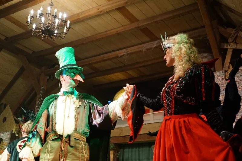 Maskentanz mit der Gräfin in Rot – Ein maskierter Herr mit grünem Hut tanzt mit der Gräfin in rotem Kleid, während das Musical-Fest seinen Höhepunkt erreicht.