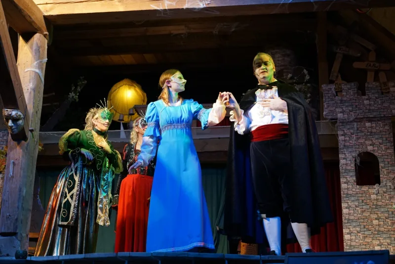 Luise tanzt mit Graf Dracula beim Maskenball – Die junge Luise in blauem Kleid tanzt mit Graf Dracula, während Gräfin Raja und Akira die Szene beobachten.