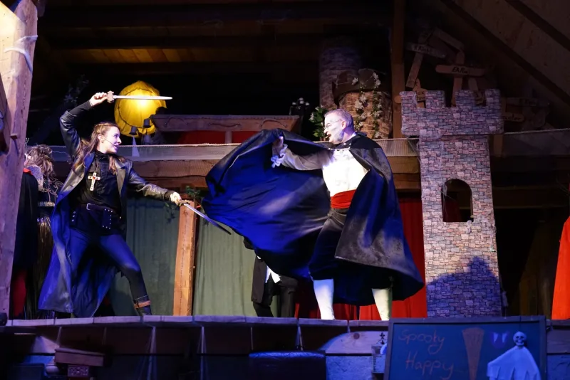 Heldin Julia kämpft gegen Graf Dracula – Die Heldin mit Schwert und Kreuz stellt sich mutig Graf Dracula im schwarzen Umhang zum Kampf auf der Bühne.