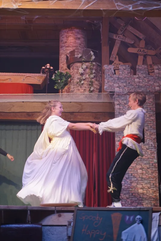Enya tanzt mit Conan im weißen Gewand – Enya im strahlend weißen Kleid tanzt lachend mit Conan, die Szene voller Leichtigkeit und Hoffnung nach dem Kampf.